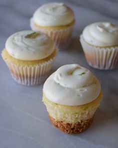 four cupcakes with white frosting and green sprinkles on top