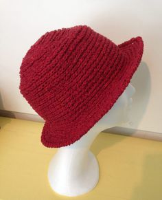 a red knitted hat sitting on top of a white mannequin head