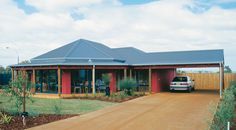 a car is parked in front of a red building with a blue roof and two cars are parked on the driveway