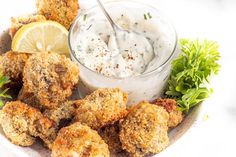 a white plate topped with fried food next to a bowl of ranch dressing