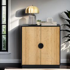 a wooden cabinet sitting in front of a window next to a potted plant and lamp