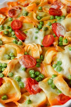 a casserole dish with peas, tomatoes and ravioli in a white bowl