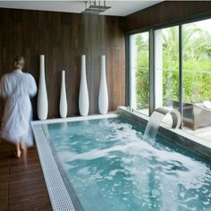 an indoor hot tub with water coming out of it and three white vases on the wall