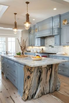 an island made out of tree trunks in the middle of a kitchen with blue cabinets