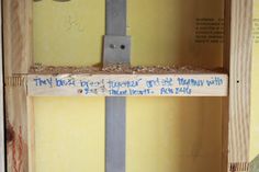 a wooden shelf with some blue writing on the bottom and yellow walls in the background