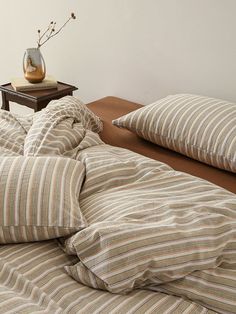 a bed with striped comforter and pillows on top of it next to a table