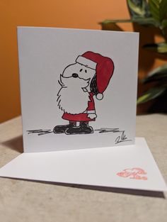 a greeting card with a drawing of a santa clause holding a red hat on top of his head