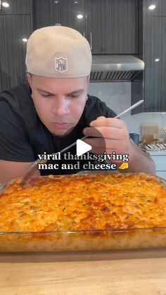 a man in a baseball cap is looking at a large cheesy casserole