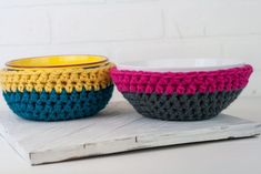 two crocheted bowls sitting next to each other