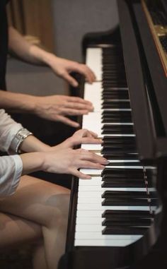 two people are sitting at a piano playing the music on it's own hands