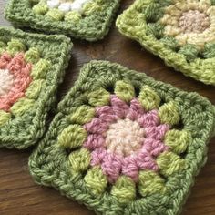 four crocheted square coasters on a wooden table with one in the center