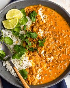 a bowl filled with rice, meat and cilantro garnished with lime