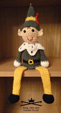 a crocheted doll sitting on top of a wooden shelf in a bookcase