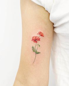 a small red flower tattoo on the right arm