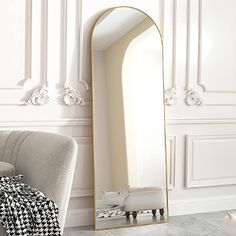 a mirror sitting on top of a white wall next to a chair