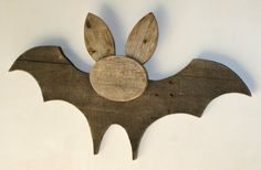 a wooden bat with ears hanging from it's side on a white wall in the shape of a house