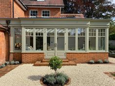 an orange brick building with glass doors and windows on the side of it, surrounded by gravel