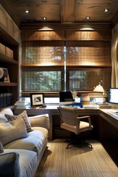 a home office with two computer desks and a couch in front of the window