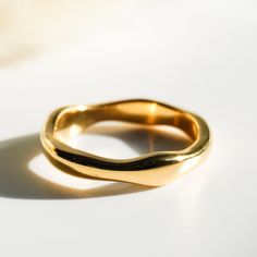 a close up of a gold ring on a white surface with light coming through it