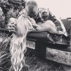 a man and woman kissing in the back of a pick up truck with long blonde hair