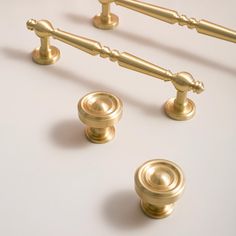 three golden knobs and two handles on a white surface