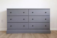 a large gray dresser sitting on top of a hard wood floor next to a white wall