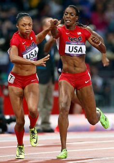 two women in red uniforms running on a track