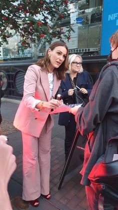 a woman in pink suit standing next to a man