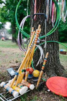 an assortment of croquets and other items sitting on the ground next to a tree