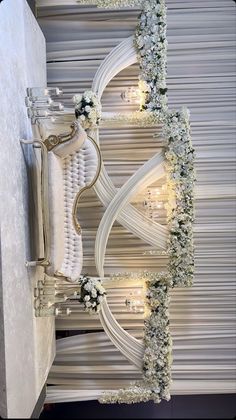 an elaborately decorated room with white flowers and greenery on the wall, along with candles