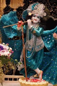 a statue of a woman holding a stick in her hand and wearing a blue outfit