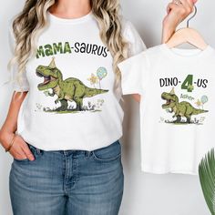 a woman is holding up a t - shirt with an image of a dinosaur on it