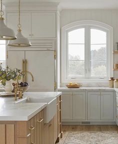 a kitchen with white cabinets and gold accents