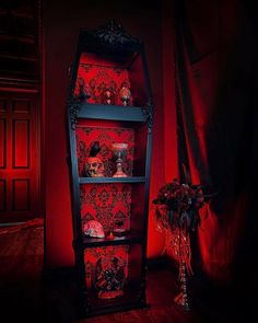 an ornate display case with red lighting in a dark room next to a vase filled with flowers