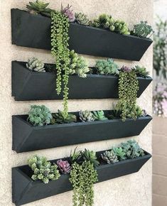 three black planters with succulents hanging on the wall