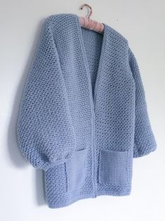 a blue knitted sweater hanging on a white wall next to a wooden hanger