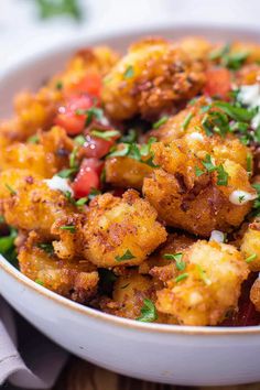 a white bowl filled with fried food on top of a wooden table