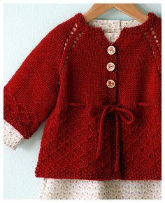 a red knitted sweater with buttons on the front and back, attached to a wooden hanger