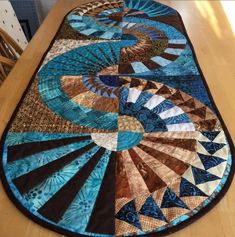 a table top with a blue and brown quilt on it's center piece, sitting on a wooden table