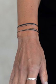 a woman's hand with two thin bracelets on her left wrist and one in the middle