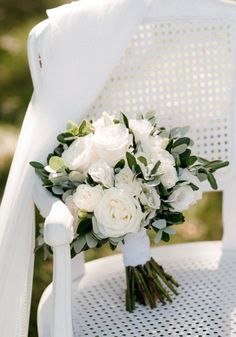 a bridal bouquet sitting on top of a white chair