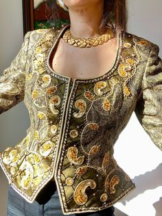 "This is a real work of art by the infamous and glamorous Victoria Royal! I cant imagine the amount of time it took to create this sculptural peplum jacket. The fabric is brocade in a paisley print with exquisite hand beaded glass and resin crystals, gold thread, pearls and sequins. The scooped neckline is adorned, so are the cuffs and the stunning peplum. This piece was an exclusive for Gazebo, a high end store in Dallas that closed decades ago. Excellent Vintage Condition Labeled 10 Laid Flat: 16\" Shoulders 19\" Bust 15\" Waist 21\"Peplum 20.5\" Long 22.5\" Sleeves" Fitted Gold Silk Outerwear, Fitted Party Outerwear With Intricate Embroidery, Luxury Fitted Outerwear With Gold Embroidery, Luxury Fitted Outerwear With Intricate Embroidery, Elegant Fitted Outerwear With Gold Embroidery, Fitted Gold Embroidered Outerwear, Festive Fitted Brocade Outerwear, Fitted Party Outerwear With Gold Embroidery, Vintage Fitted Outerwear For Festive Occasions