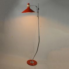 a floor lamp with a red shade on the base and a white light behind it