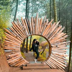 a woman taking a photo in front of a mirror made out of wooden sticks and logs