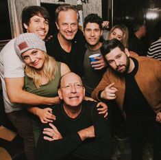 a group of people standing around each other posing for the camera with their arms around one another