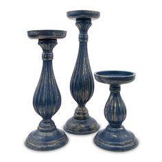 three blue candlesticks sitting next to each other on top of a white surface