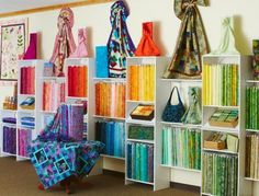 a room filled with lots of different colored bags and bookshelves on white shelving units