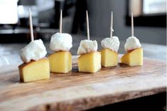 four pieces of cheese are sitting on a cutting board with toothpicks sticking out of them