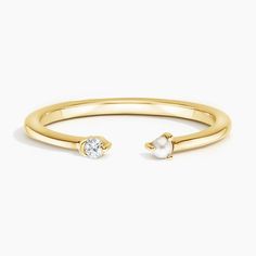 a yellow gold ring with a single pearl on the side and a diamond in the middle