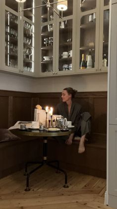 a woman sitting at a table with candles in front of her on top of the table